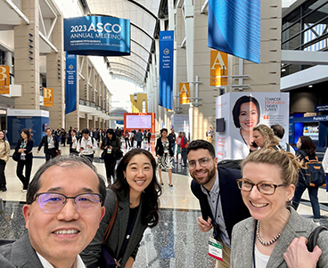 Four smiling Bluestar team members take selfie in lively trade show hall