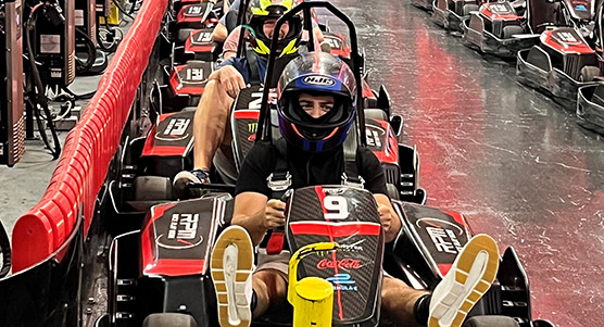 Bluestar team member, helmeted, seated in mini race car, ready for competition driving